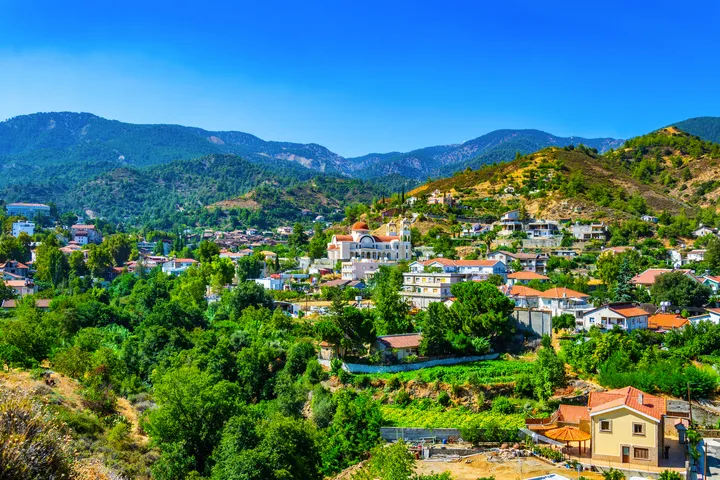 © dudlajzov - stock.adobe.com Blick auf ein malerisches Dorf in einer grünen, bergigen Landschaft bei sonnigem Wetter.