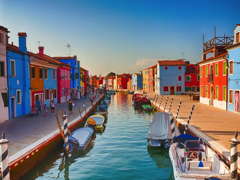 Bunte Häuser und Boote entlang eines Kanals in Burano, Italien.