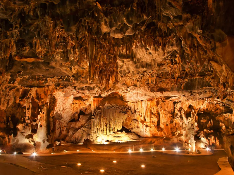 Beleuchtete Höhle mit Stalagmiten und Stalaktiten.
