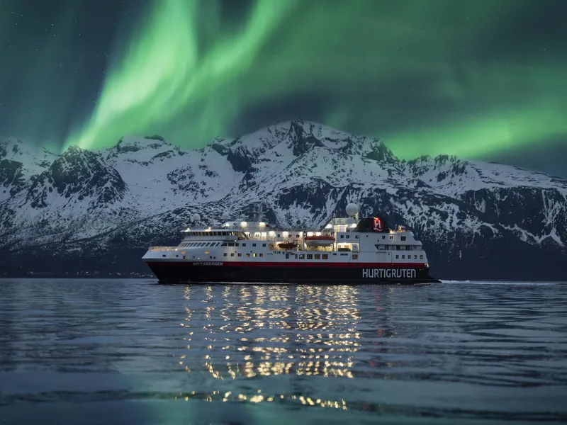Schiff der Hurtigruten vor Nordlichtern in Norwegen.