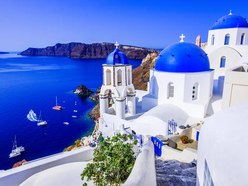 Weiße Gebäude mit blauen Kuppeln und Meerblick auf Santorin, Griechenland.