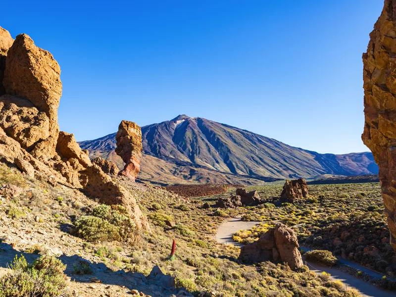 Vulkanlandschaft mit Berg und Felsen unter blauem Himmel.