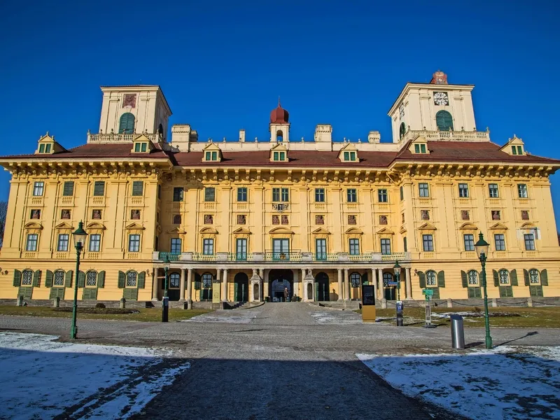 Großes gelbes Barockschloss an einem klaren Tag mit blauem Himmel.