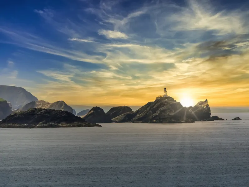 Blick auf den Leuchtturm auf der Insel Unst, der nördlichsten der Shetlandinseln, bei Sonnenuntergang.
