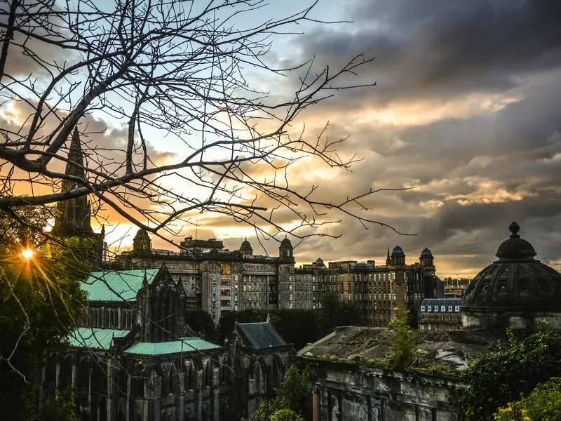Glasgow im Winter mit historischen Gebäuden und bewölktem Himmel bei Sonnenuntergang.