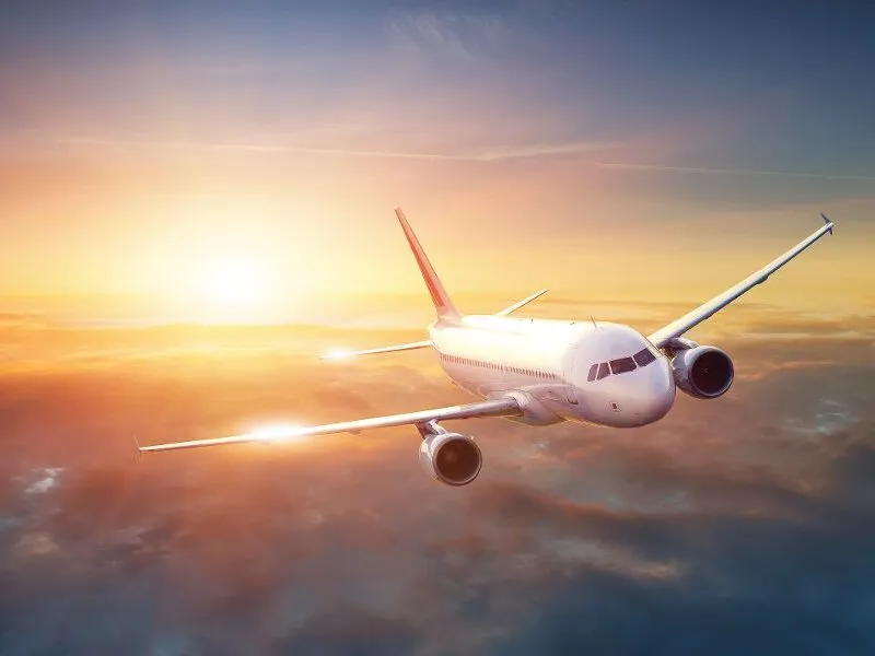 Ein Verkehrsflugzeug fliegt über den Wolken während des Sonnenuntergangs.