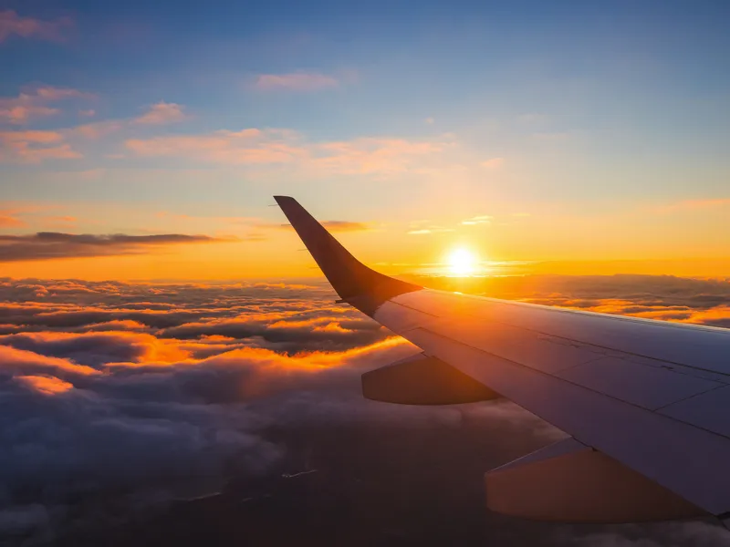 Flugzeugflügel im Sonnenuntergang über den Wolken.