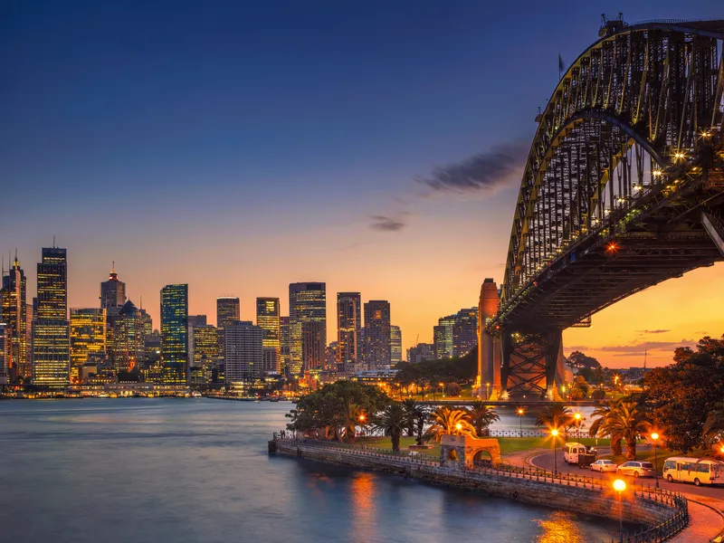Skyline von Sydney bei Sonnenuntergang mit der Harbour Bridge im Vordergrund.