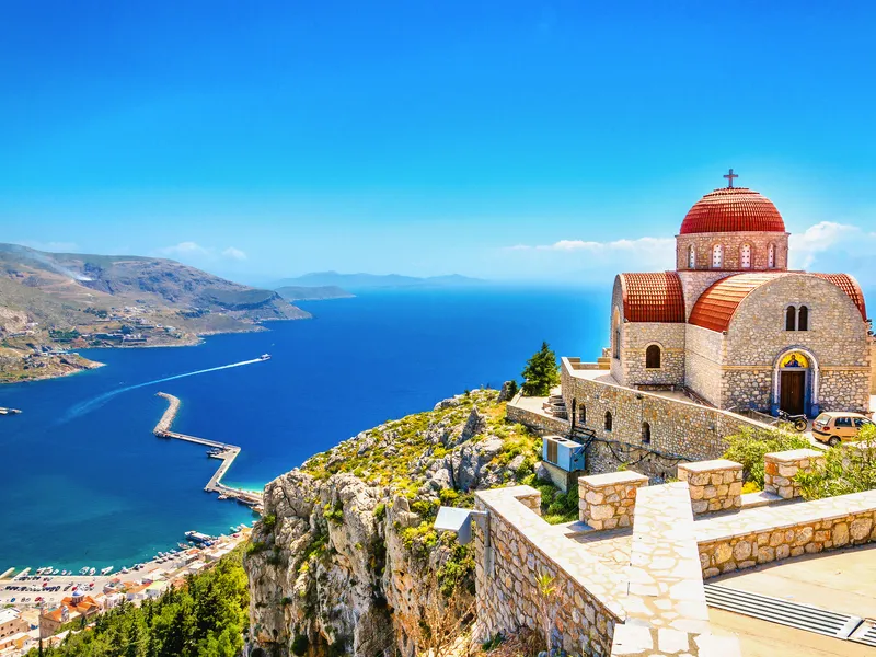 Kirche mit rotem Dach auf Klippe, Blick aufs Meer und Hafen.