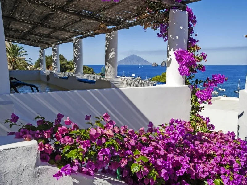 Sommerterrasse mit Bougainvillea und Meerblick auf Insel.