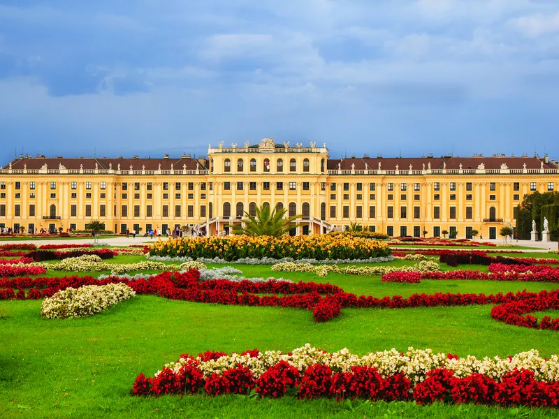 Barockschloss mit aufwendig gestalteten Blumenbeeten im Vordergrund.