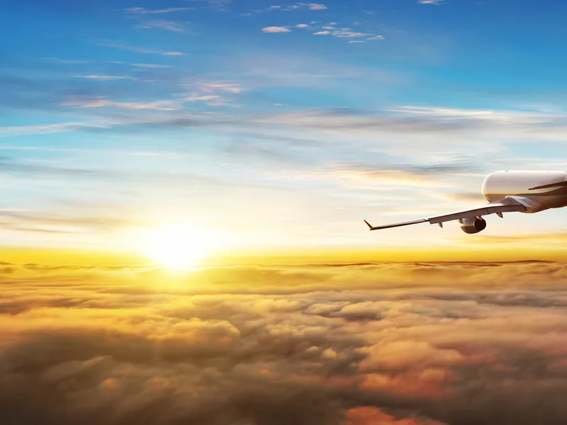 Flugzeug fliegt über Wolken im Sonnenuntergang