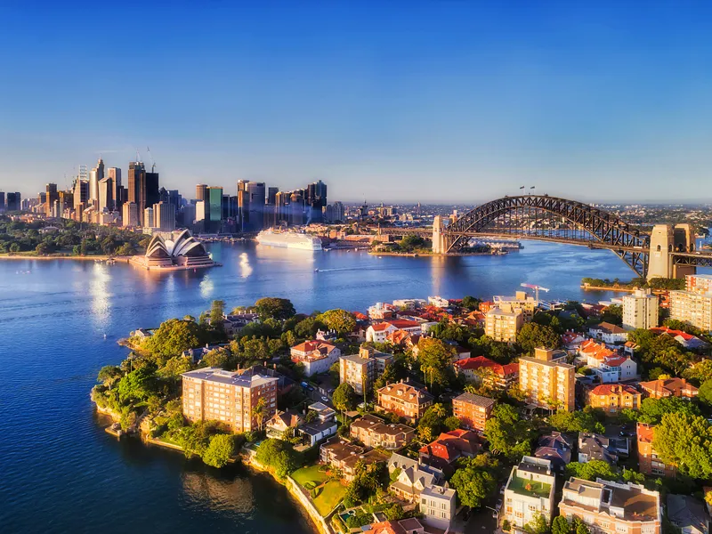 Luftaufnahme von Sydney mit Opernhaus und Hafenbrücke bei klarem Himmel.