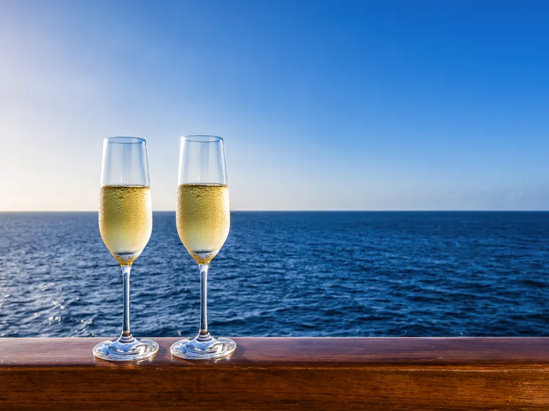 Zwei Sektgläser auf einer Reling mit Blick auf das Meer.