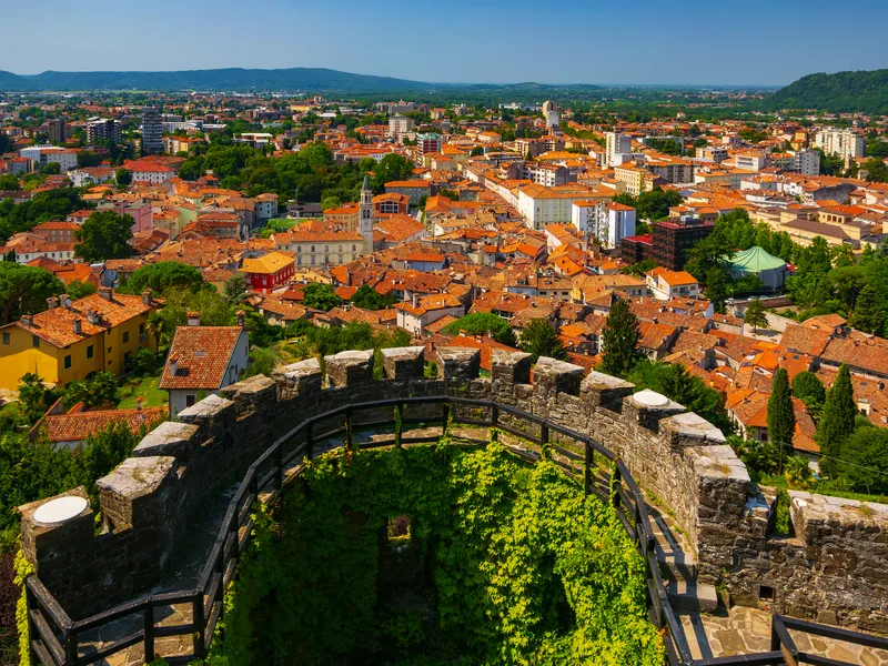 Stadtansicht mit Burgmauer im Vordergrund und Hügel im Hintergrund.