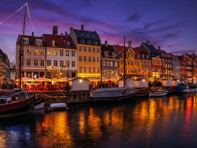 Abendstimmung mit beleuchteten Häusern und Booten an einem Kanal.