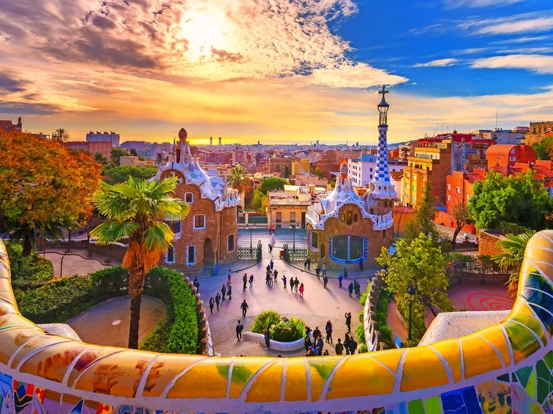 Park Güell mit bunten Mosaiken und Blick auf Barcelona bei Sonnenuntergang.