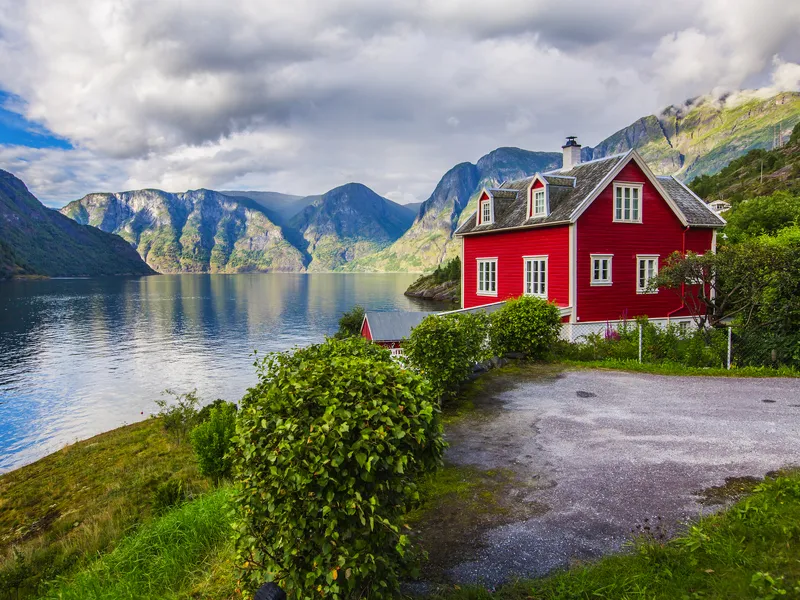 Rotes Haus am Faleidfjord in Olden, Norwegen, umgeben von beeindruckender Fjordlandschaft.