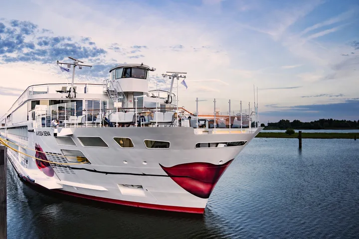 Kreuzfahrtschiff A-ROSA Sena auf dem Fluss Rhein bei Sonnenuntergang.