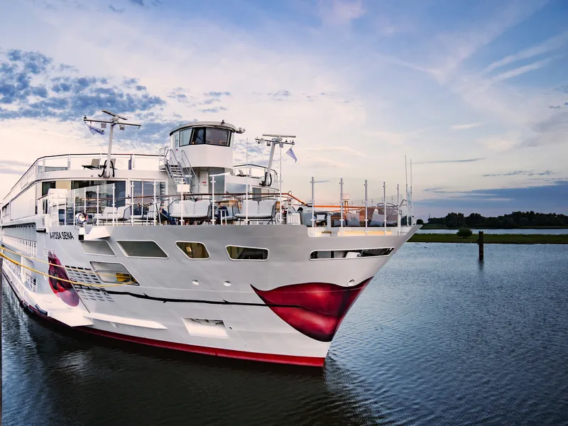 Kreuzfahrtschiff A-ROSA Sena auf dem Fluss Rhein bei Sonnenuntergang.