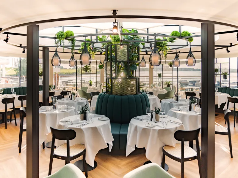 Elegantes Restaurant mit runden Tischen und moderner Begrünung.