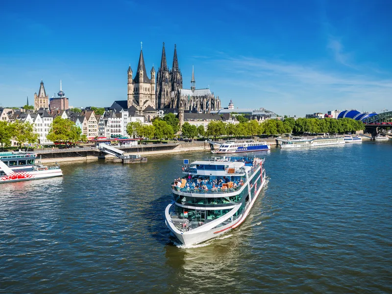 Kreuzfahrtschiff auf dem Rhein vor dem Kölner Dom bei sonnigem Wetter.