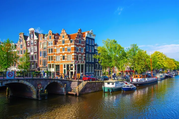 Kanal in Amsterdam mit Booten und alten Gebäuden bei sonnigem Wetter