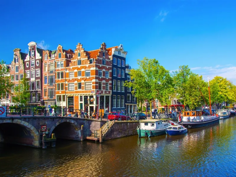 Kanal in Amsterdam mit Booten und alten Gebäuden bei sonnigem Wetter