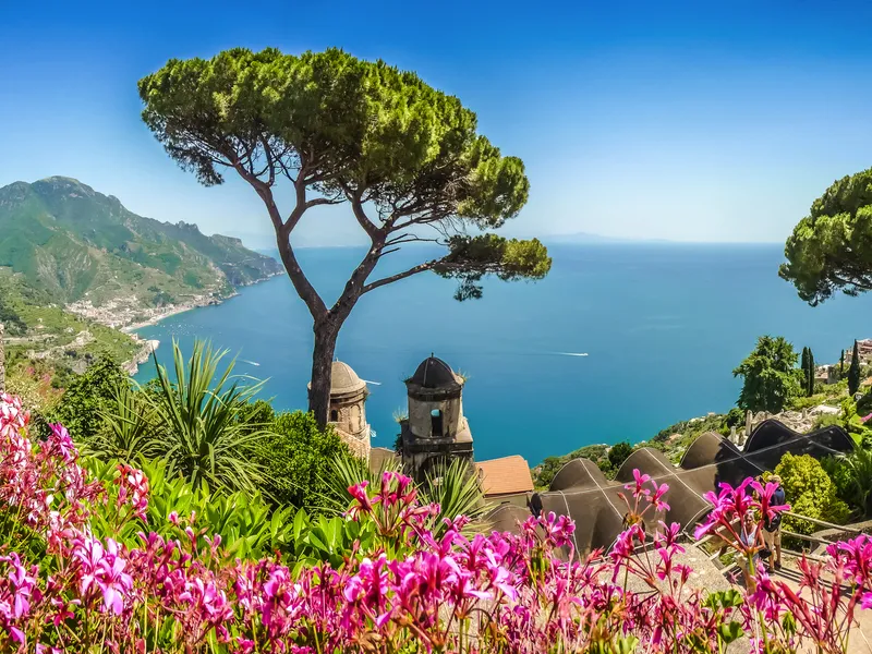 Garten mit Blumen und Bäumen, Blick auf Küste und Meer.