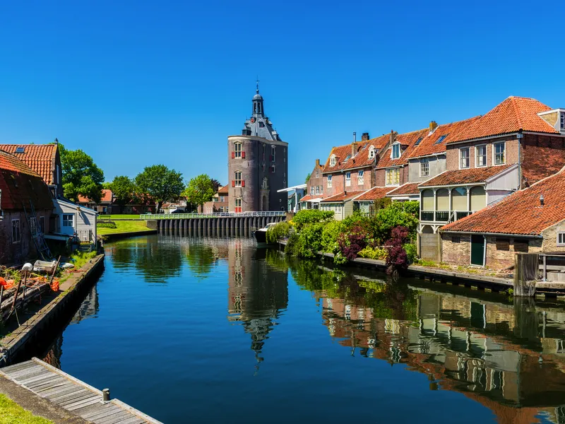Historische Gebäude und ein Turm am Wasser mit klarem Himmel.